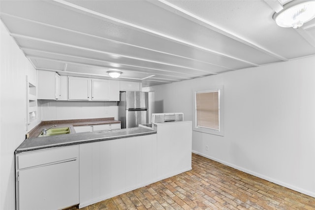 kitchen with white cabinets, sink, and stainless steel fridge