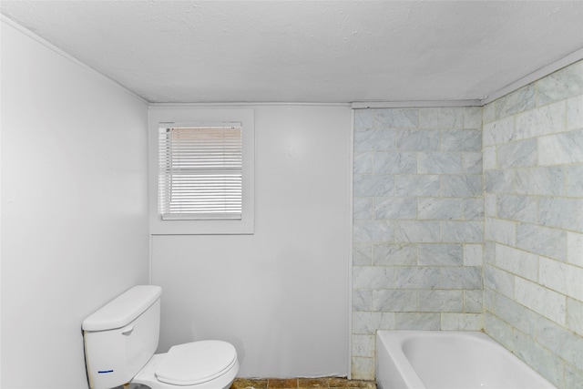 bathroom with a bath, toilet, and a textured ceiling