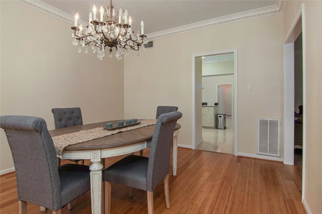 dining area featuring crown molding, an inviting chandelier, and light hardwood / wood-style floors