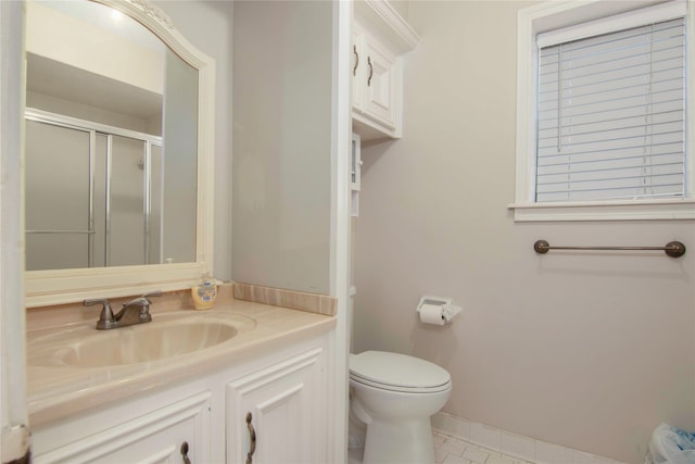 bathroom featuring vanity, a shower with shower door, and toilet