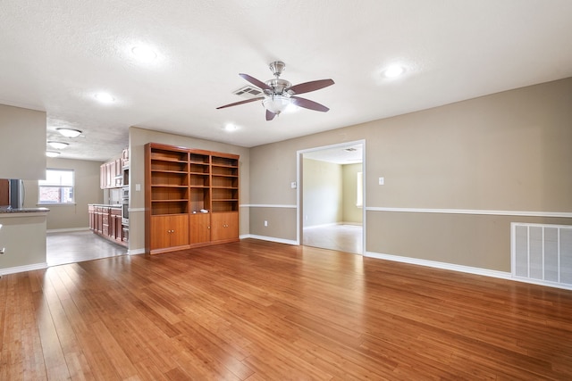 unfurnished living room featuring ceiling fan, wood-type flooring, and a textured ceiling