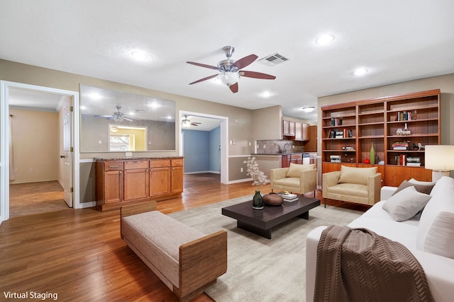 living room with sink, ceiling fan, and light hardwood / wood-style flooring