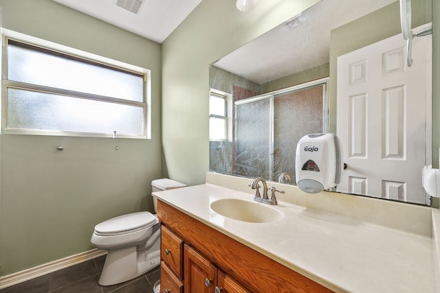 bathroom featuring tile patterned flooring, walk in shower, vanity, and toilet