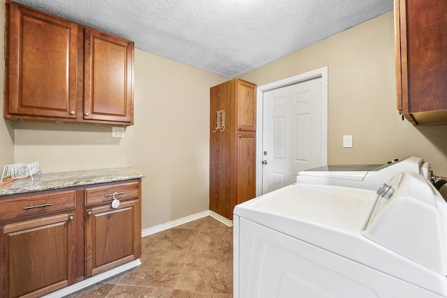 laundry room featuring independent washer and dryer, cabinets, and a textured ceiling