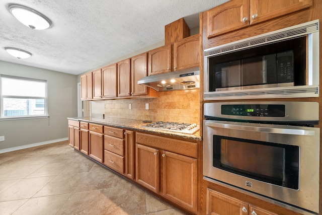 kitchen with built in microwave, light tile patterned flooring, gas stovetop, oven, and backsplash