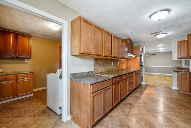 kitchen with washer / clothes dryer, backsplash, stainless steel gas cooktop, and a textured ceiling