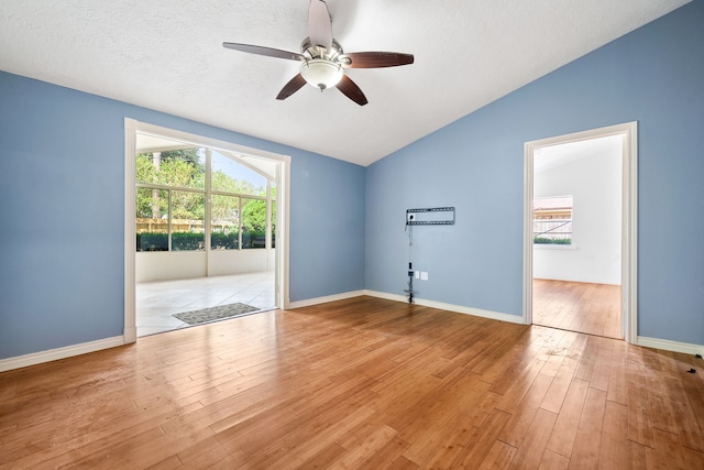 unfurnished room featuring ceiling fan, lofted ceiling, a textured ceiling, and light wood-type flooring