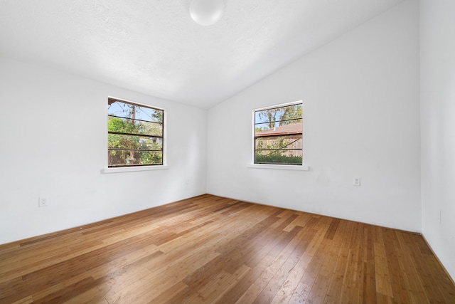 unfurnished room featuring a textured ceiling, vaulted ceiling, and wood-type flooring