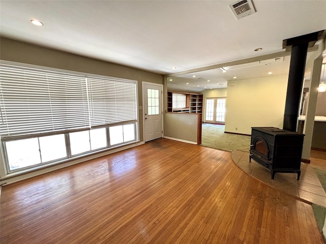 unfurnished living room featuring hardwood / wood-style floors and a wood stove