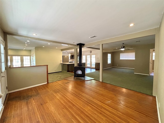 interior space featuring hardwood / wood-style flooring, a wood stove, and ceiling fan