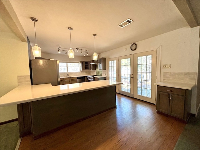 kitchen featuring appliances with stainless steel finishes, dark hardwood / wood-style floors, hanging light fixtures, kitchen peninsula, and french doors