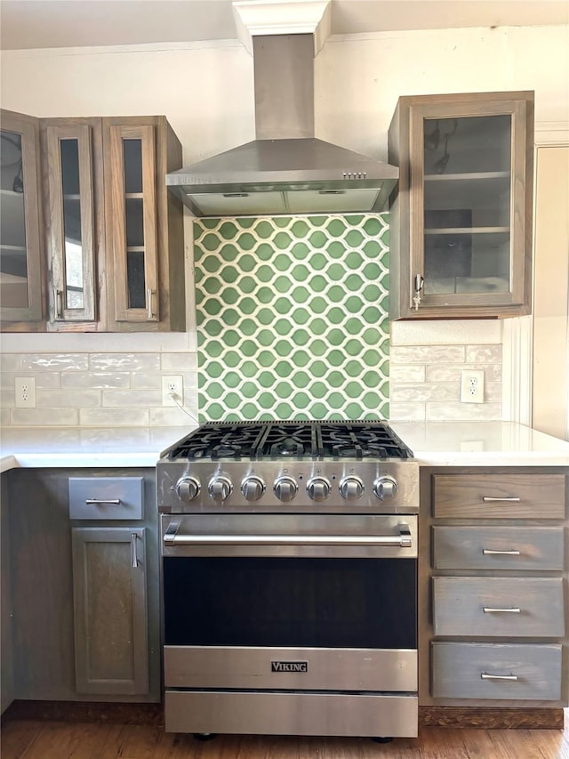 kitchen featuring dark brown cabinets, wall chimney range hood, stainless steel range, and backsplash