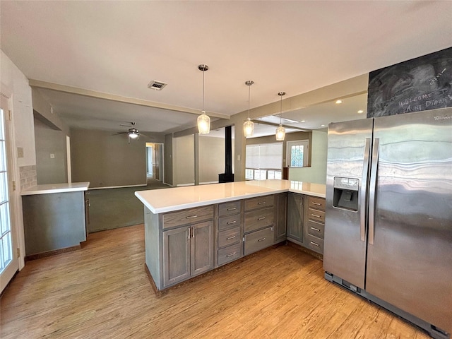 kitchen with stainless steel refrigerator with ice dispenser, kitchen peninsula, pendant lighting, ceiling fan, and light hardwood / wood-style floors