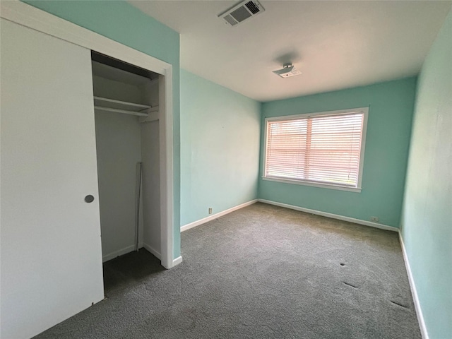 unfurnished bedroom featuring a closet and dark colored carpet