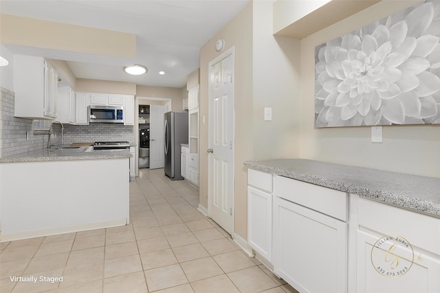 kitchen with sink, light tile patterned floors, appliances with stainless steel finishes, white cabinets, and decorative backsplash