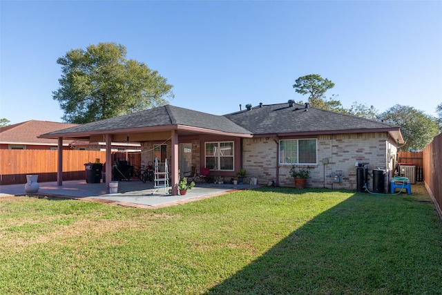 rear view of property with cooling unit, a yard, and a patio area