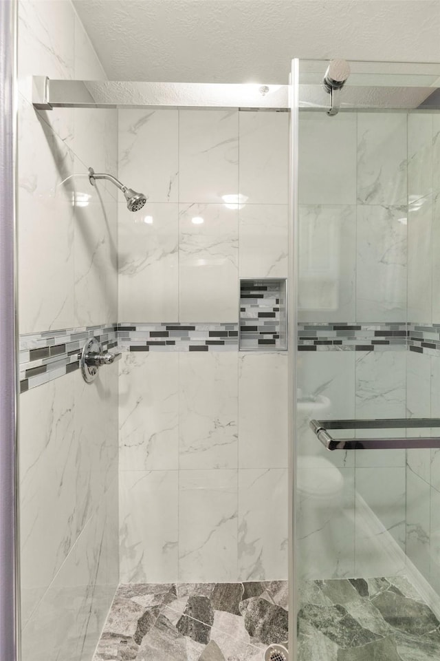 bathroom with an enclosed shower and a textured ceiling