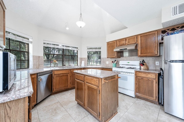 kitchen with tasteful backsplash, decorative light fixtures, a center island, and appliances with stainless steel finishes