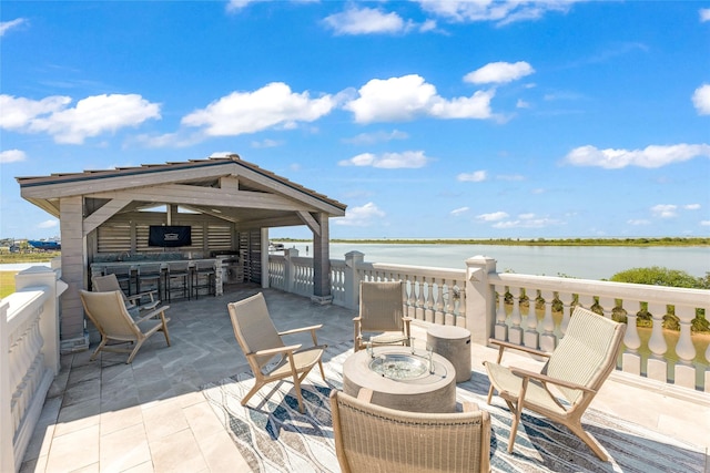 view of patio featuring an outdoor fire pit, an outdoor bar, and a water view