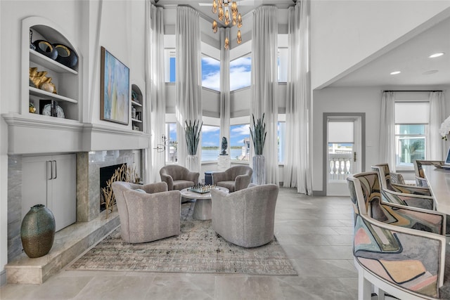 tiled living room with a premium fireplace, a towering ceiling, a wealth of natural light, and built in shelves