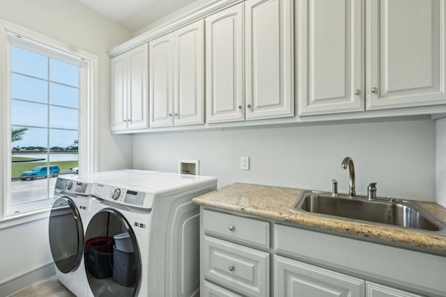 clothes washing area featuring cabinets, sink, and independent washer and dryer