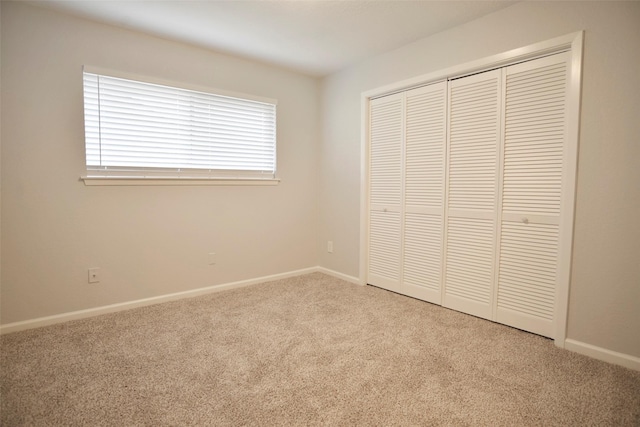 unfurnished bedroom featuring light colored carpet and a closet