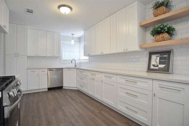 kitchen featuring sink, stainless steel appliances, white cabinets, dark hardwood / wood-style flooring, and decorative light fixtures