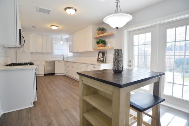 kitchen with appliances with stainless steel finishes, wood counters, white cabinetry, sink, and hanging light fixtures