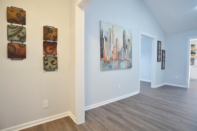 corridor with dark hardwood / wood-style flooring and lofted ceiling