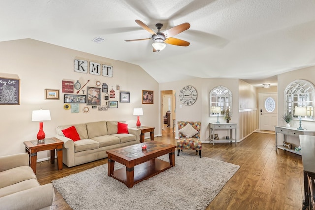 living room featuring ceiling fan, dark hardwood / wood-style floors, vaulted ceiling, and a textured ceiling