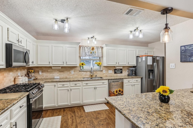 kitchen featuring dark hardwood / wood-style floors, sink, white cabinets, hanging light fixtures, and stainless steel appliances