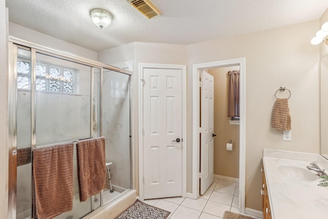 bathroom featuring a shower with door, vanity, tile patterned floors, and a textured ceiling