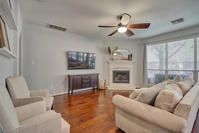 living room featuring ceiling fan, dark hardwood / wood-style floors, and a textured ceiling