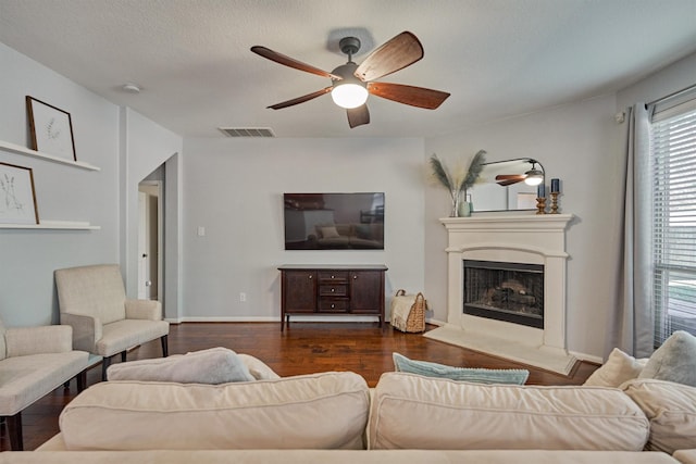 living room with ceiling fan, a textured ceiling, and dark hardwood / wood-style flooring