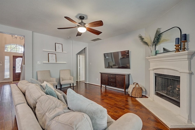 living room featuring dark wood-type flooring, a textured ceiling, and ceiling fan