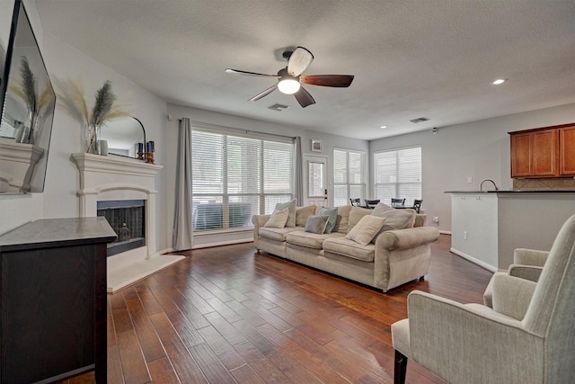 living room featuring ceiling fan, sink, a textured ceiling, and dark hardwood / wood-style flooring