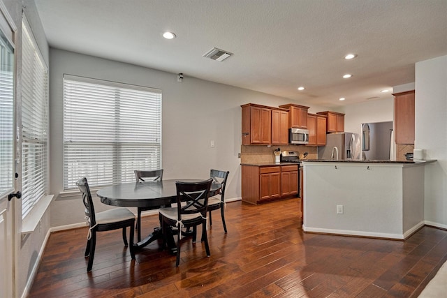 dining room with a textured ceiling and dark hardwood / wood-style flooring