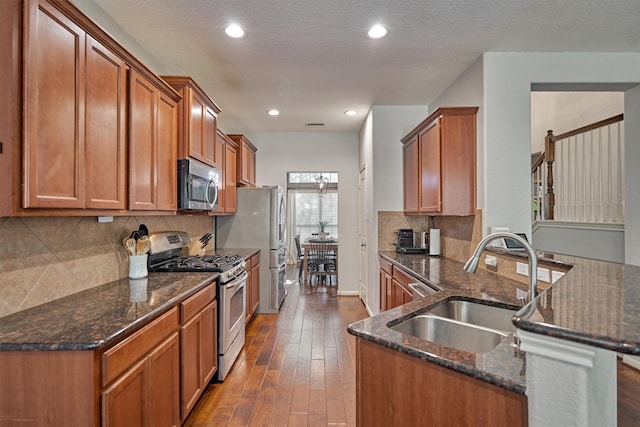 kitchen featuring appliances with stainless steel finishes, kitchen peninsula, sink, and dark stone counters