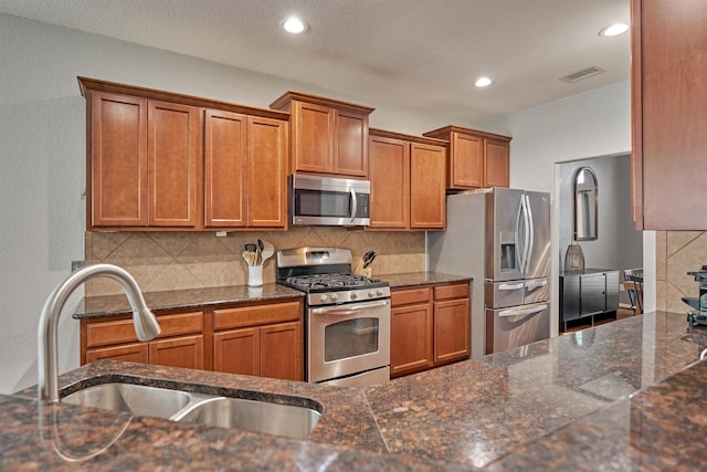 kitchen featuring dark stone countertops, sink, backsplash, and stainless steel appliances