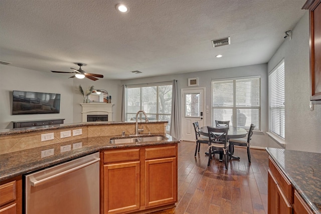 kitchen with dishwasher, sink, dark stone countertops, ceiling fan, and dark wood-type flooring