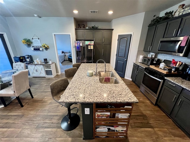 kitchen with stainless steel appliances, a kitchen breakfast bar, sink, and a center island with sink