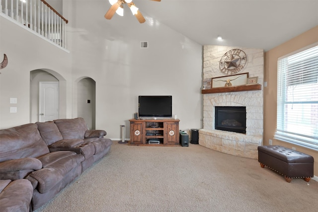 carpeted living room with ceiling fan, high vaulted ceiling, and a fireplace