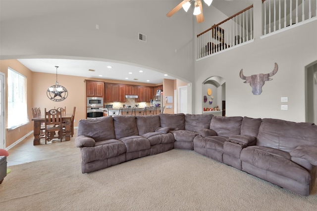 tiled living room with ceiling fan and a towering ceiling