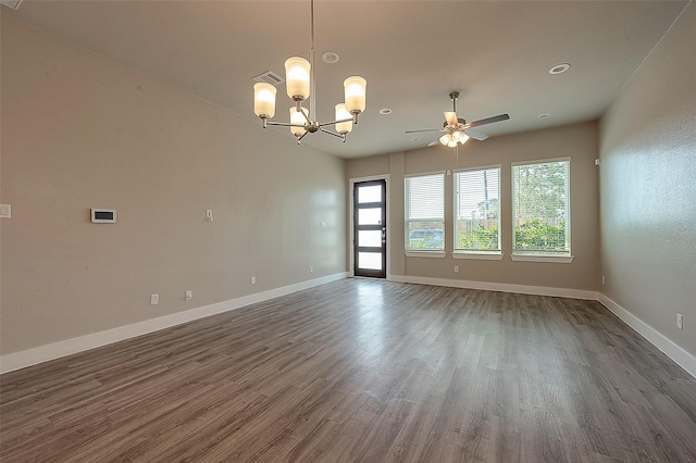 empty room featuring dark wood-type flooring, a wealth of natural light, and ceiling fan with notable chandelier