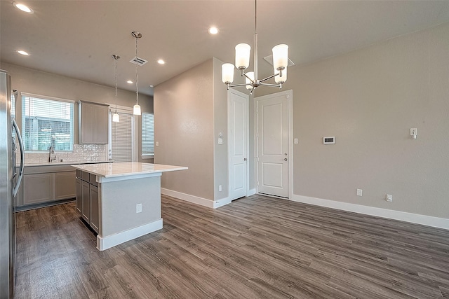 kitchen featuring gray cabinets, decorative light fixtures, tasteful backsplash, dark hardwood / wood-style flooring, and a center island