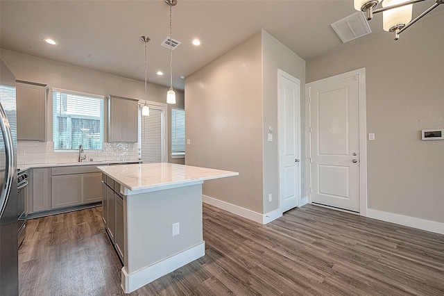 kitchen with gray cabinets, dark hardwood / wood-style floors, backsplash, hanging light fixtures, and a center island