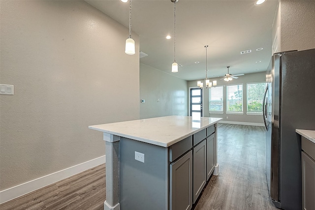 kitchen with stainless steel refrigerator, pendant lighting, a center island, and gray cabinetry