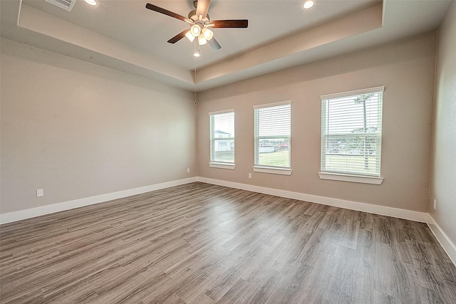 empty room featuring a tray ceiling, ceiling fan, and hardwood / wood-style flooring