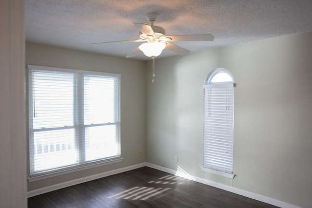 unfurnished room with dark hardwood / wood-style flooring, a textured ceiling, a wealth of natural light, and ceiling fan