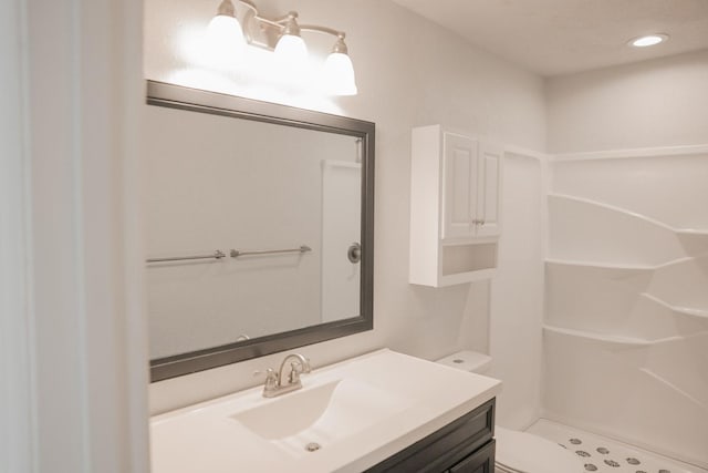 bathroom featuring vanity, a shower, and toilet